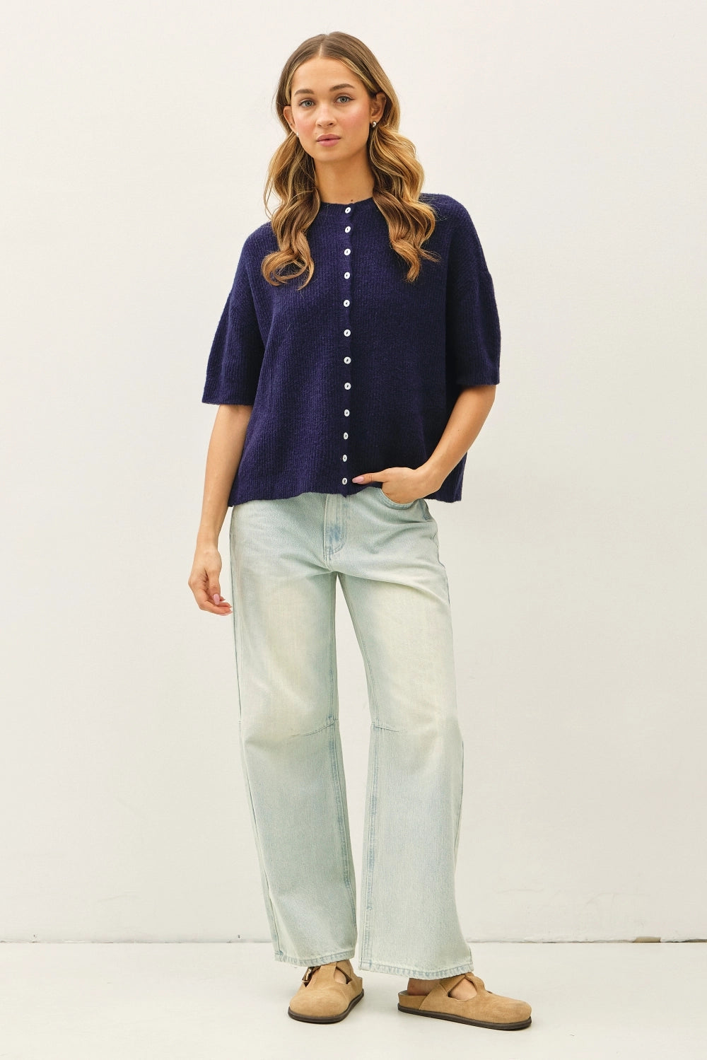 Women wearing a navy short sleeve cardigan against a neutral background. 