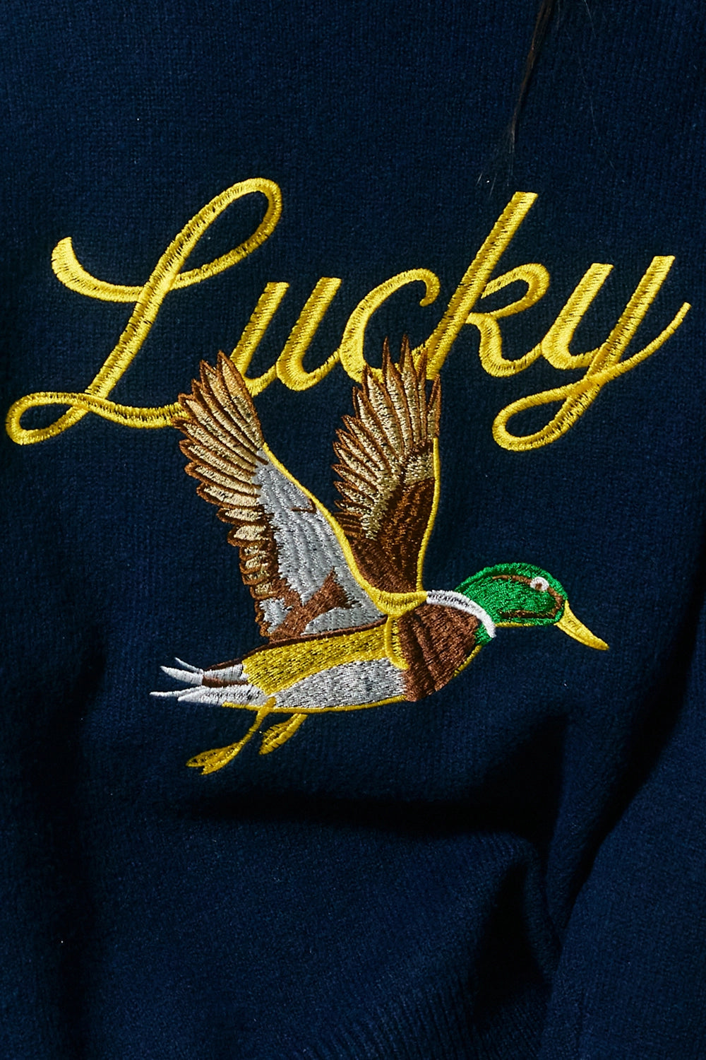 Embroidered duck and 'Lucky' text on a dark fabric background